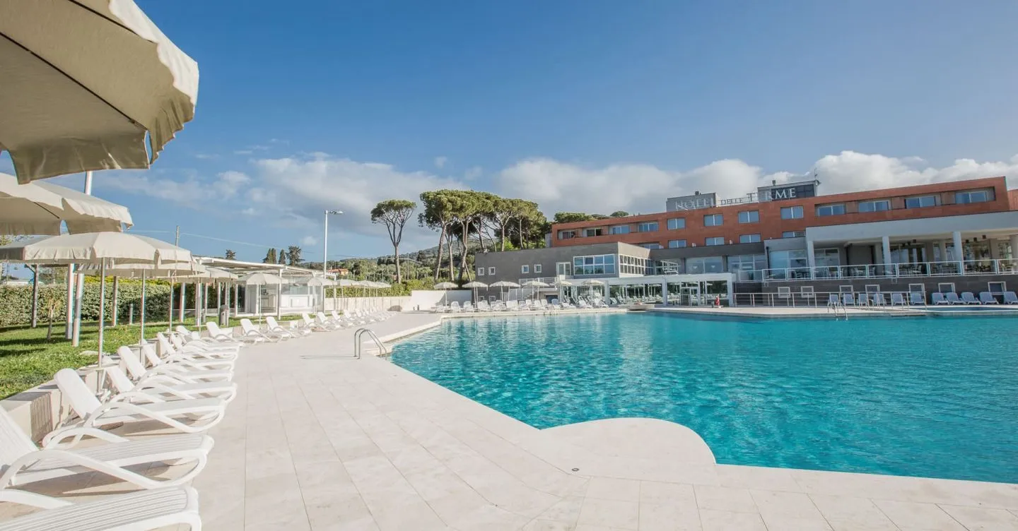 La piscina termale esterna delle Terme di Venturina, con lettini e ombrelloni davanti alla facciata dell’hotel
